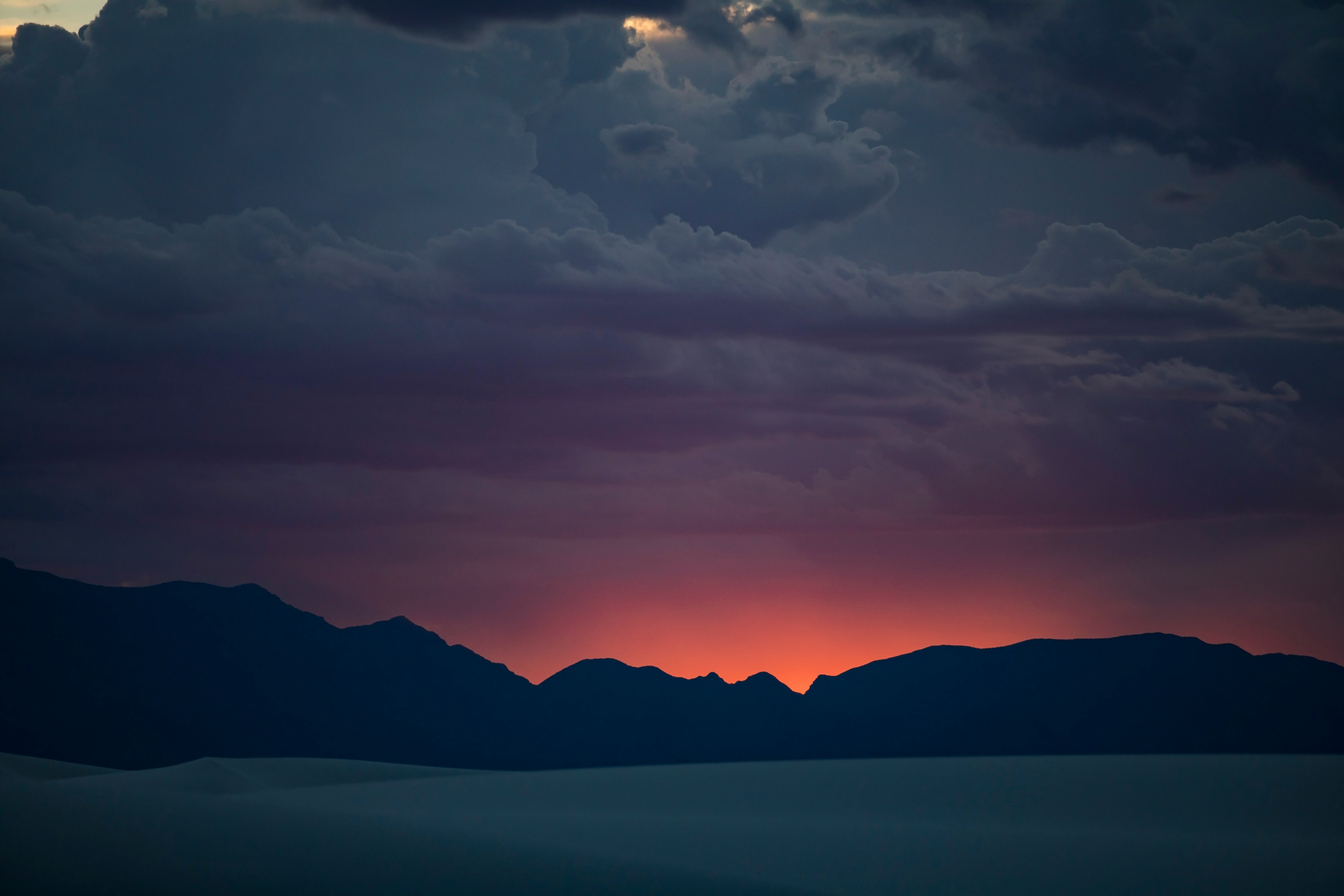 silhouette of mountain under cloudy sky during sunset